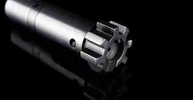 Close-up of an AR-15 bolt showing locking lugs and front face against a black background