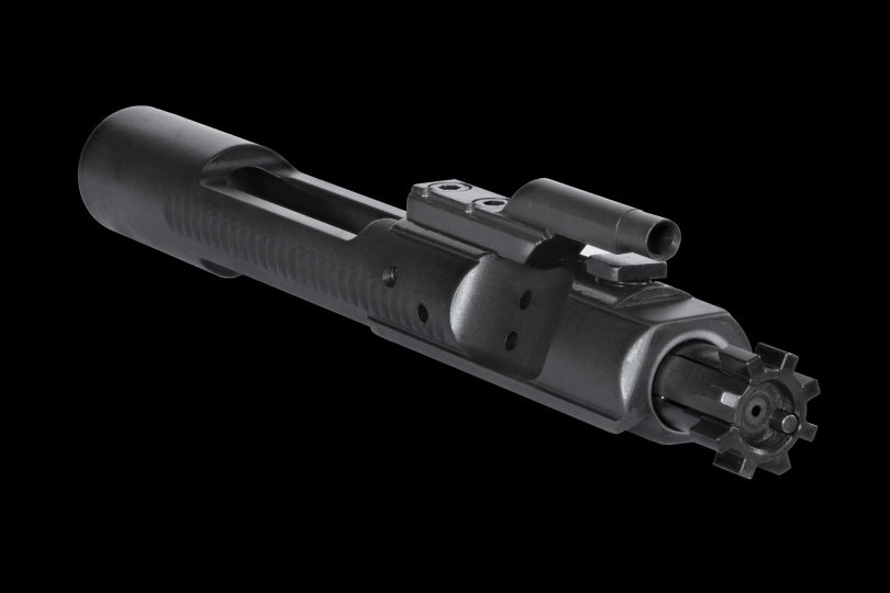 Close-up of an AR-15 bolt carrier group showing the carrier body, gas key, and bolt face against a black background