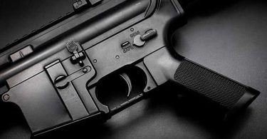 Close-up view of an AR-15 lower receiver showing the trigger, safety selector, and magazine well
