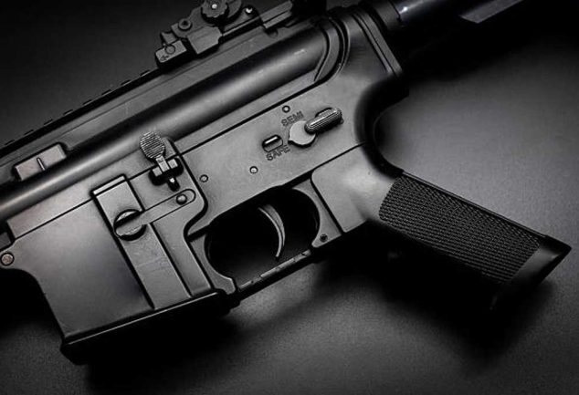 Close-up view of an AR-15 lower receiver showing the trigger, safety selector, and magazine well