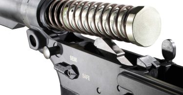 Close-up of an AR-15 lower receiver with buffer tube, buffer spring, and buffer partially removed