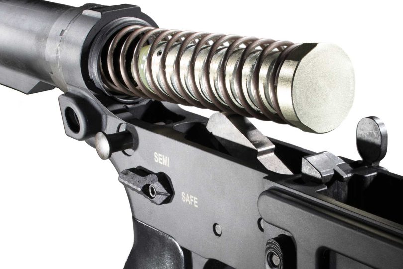 Close-up of an AR-15 lower receiver with buffer tube, buffer spring, and buffer partially removed