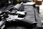 Close-up of a black AR-style rifle receiver and magazine resting on a padded surface