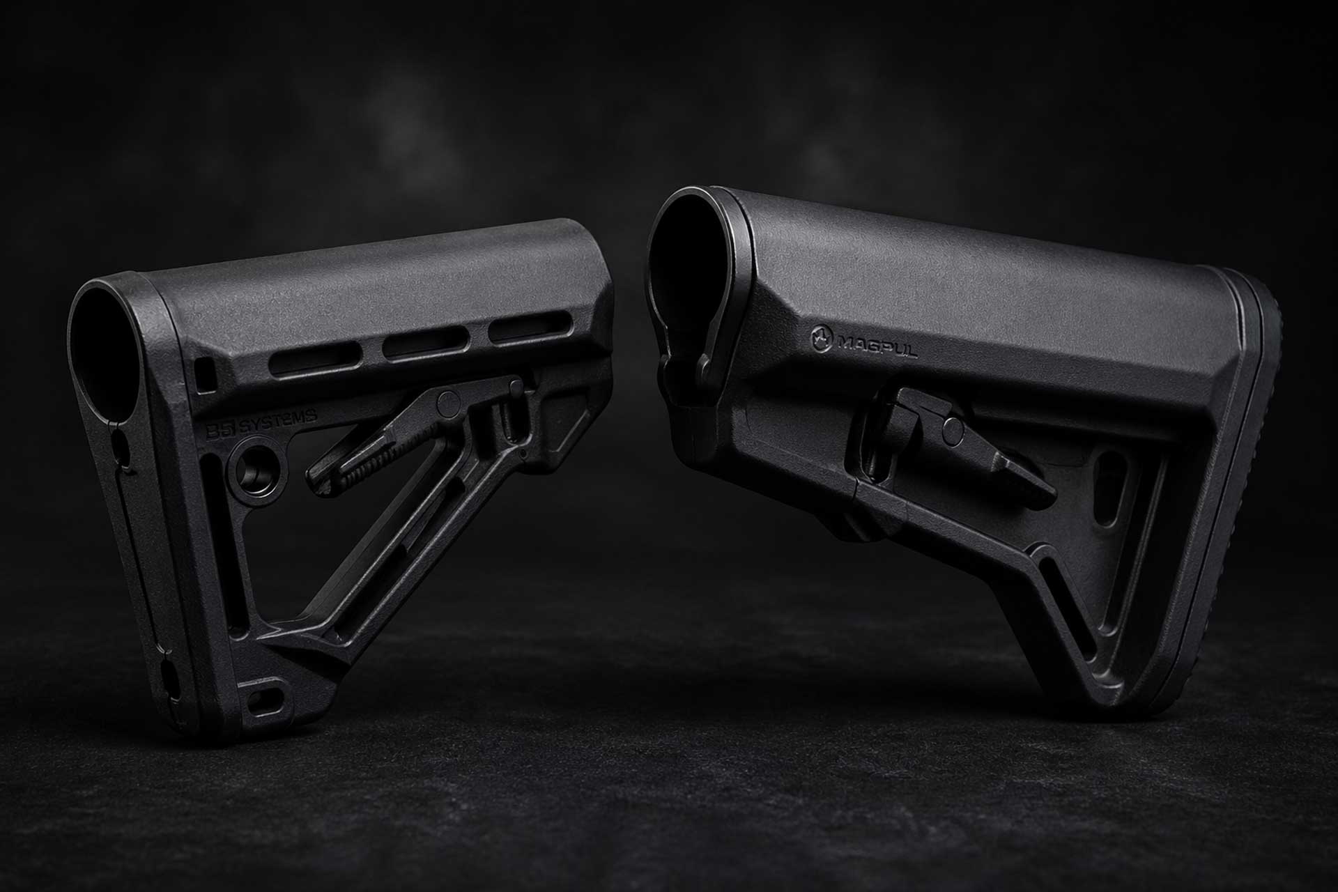 Two black AR-15 buttstocks placed facing each other on a dark textured surface with soft studio lighting