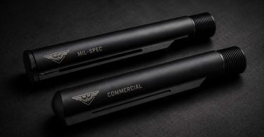 Two black AR-style buffer tubes labeled mil-spec and commercial placed side by side on a dark surface