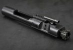 AR-15 bolt carrier group on a dark workbench showing bolt lugs and carrier body