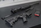 Partially assembled AR-15 with upper receiver, lower receiver, bolt carrier group, and magazine on a workbench