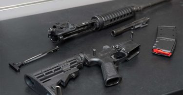 Partially assembled AR-15 with upper receiver, lower receiver, bolt carrier group, and magazine on a workbench