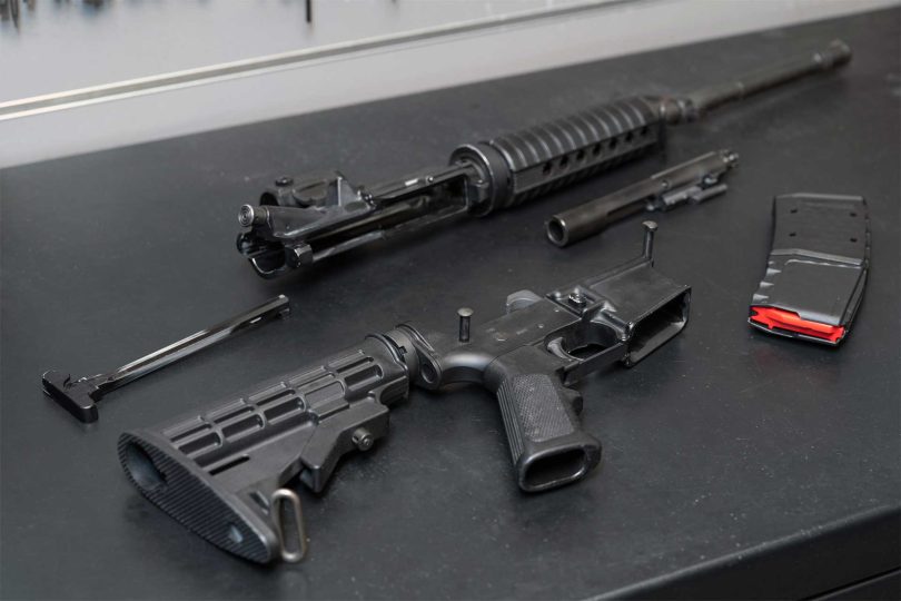 Partially assembled AR-15 with upper receiver, lower receiver, bolt carrier group, and magazine on a workbench