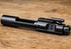 assembled AR-15 bolt carrier group resting on a wooden surface
