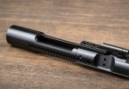 assembled AR-15 bolt carrier group resting on a wooden surface