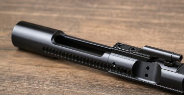 assembled AR-15 bolt carrier group resting on a wooden surface