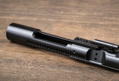 assembled AR-15 bolt carrier group resting on a wooden surface