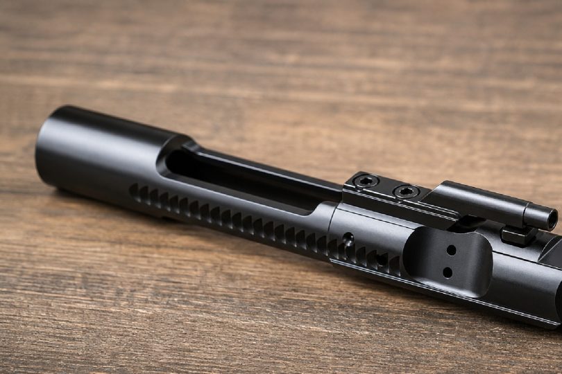 assembled AR-15 bolt carrier group resting on a wooden surface